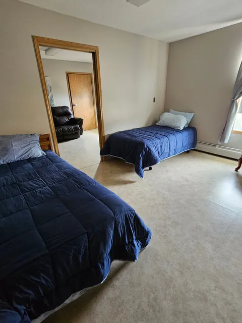 Bedroom with two single beds, blue bedding and a doorway to a sitting area.