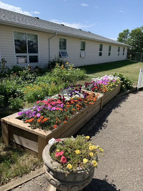 Raised flower bed and planters beside the residence and a paved path.