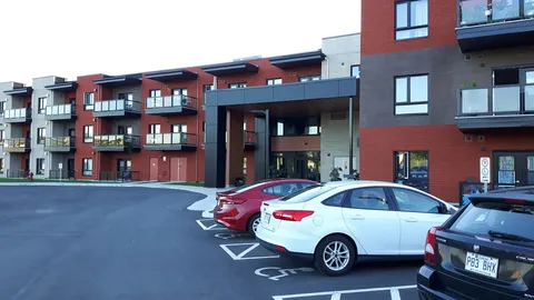 Red brick residence with balconies, a covered entrance and parked cars