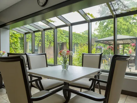 Table and white chairs beside windows overlooking a planted courtyard