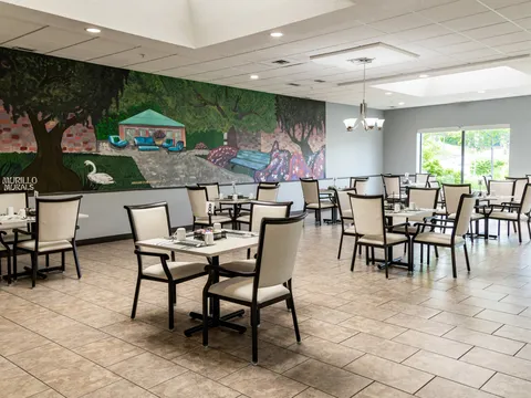 Dining room with set tables, white chairs and a colourful garden mural