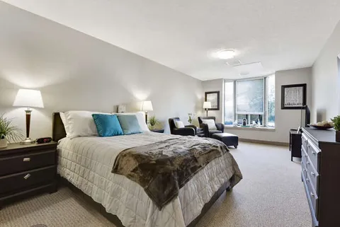 Bedroom with a double bed, blue pillows, lamps, armchairs and a window