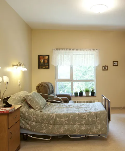 Bedroom with a single bed, a recliner, a bedside cabinet and a curtained window