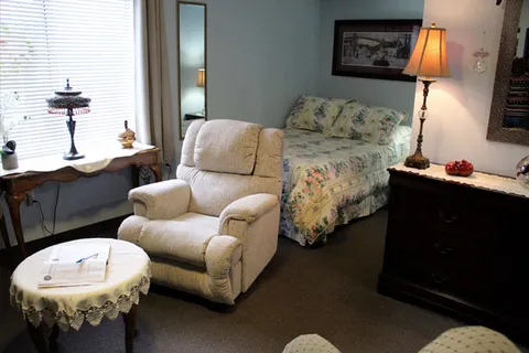 Suite with a bed, armchair, bedside lamp and bookcase.