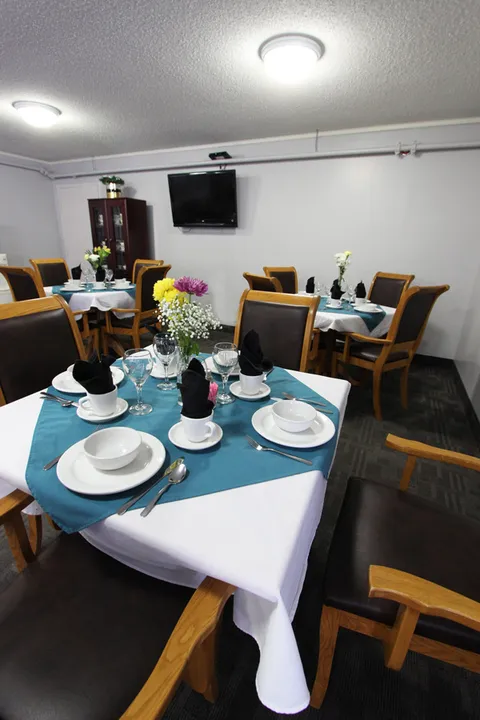 Dining room with set tables, wooden chairs and a television.