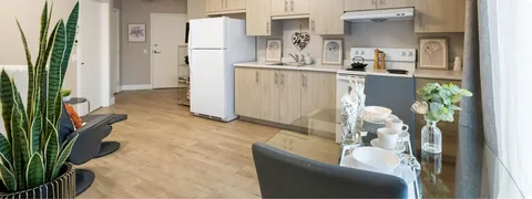 Apartment kitchenette with cabinets, a refrigerator, stove and dining table.