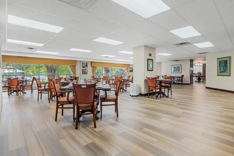 Dining room with square tables, upholstered chairs and wide windows