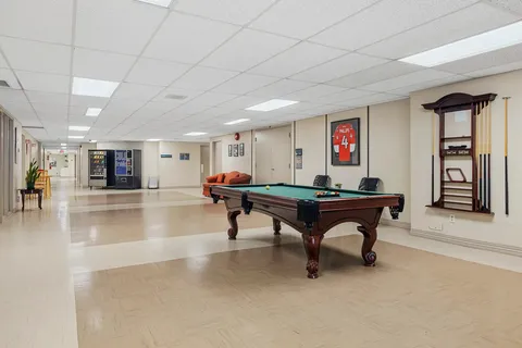 Room with a green pool table, cue rack and seating