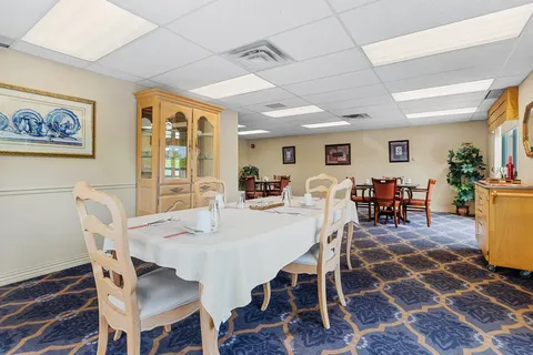 Dining table with a white cloth beside wood cabinets and smaller tables