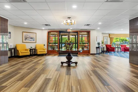 Lobby with yellow armchairs, a flower arrangement and glass entrance doors
