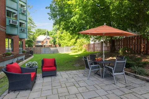 Paved patio with red-cushioned chairs and a table under a red umbrella