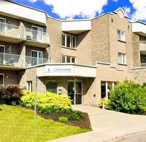 Brick residence exterior with balconies, shrubs and a covered entrance.