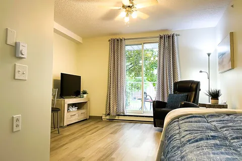 Bedroom with a bed, recliner, television and sliding balcony door.