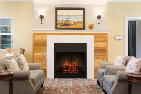 Lobby chairs and coffee table beside a fireplace.