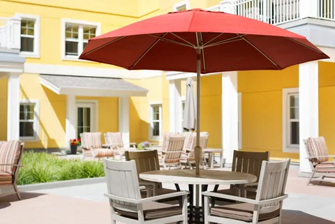 Courtyard patio with tables, wooden chairs and red umbrellas.