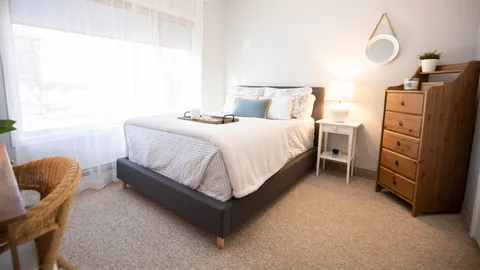 Bedroom with a double bed, wooden dresser and large window