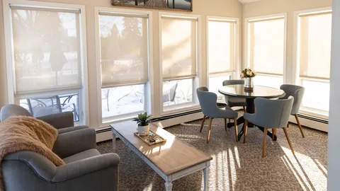 Sunlit room with armchairs, a round table and large windows