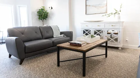 Sofa and coffee table beside a mirrored cabinet and plants
