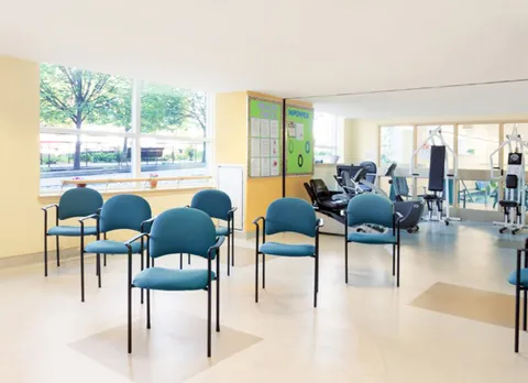 Exercise area with blue chairs and fitness machines beside large windows