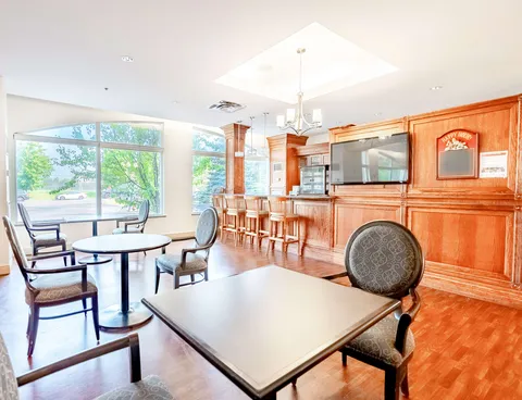 Room with tables, chairs, wooden bar counters and a blank television