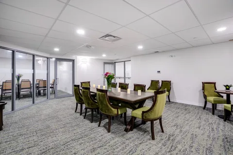Dining table with green upholstered chairs.