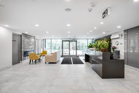 Lobby with reception desk and seating near the glass entrance.