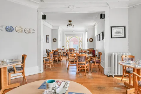Dining room with wooden chairs, set tables and stained-glass windows