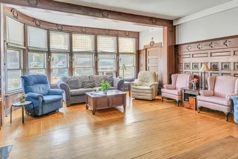 Room with armchairs, a sofa, bay windows and wooden wall panelling