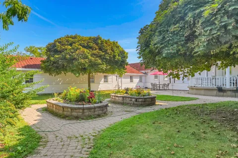 Courtyard with raised flower beds, trees, a brick path and patio seating