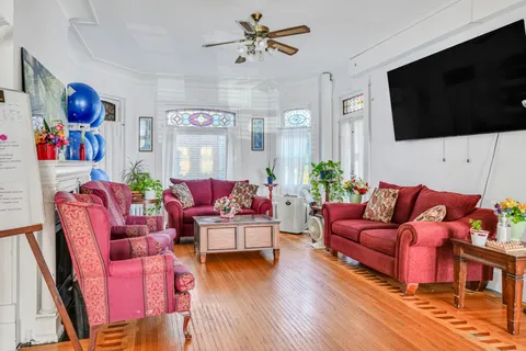 Room with red sofas and armchairs, plants and a blank wall-mounted television