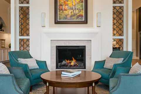 Lobby armchairs and a coffee table beside a fireplace.