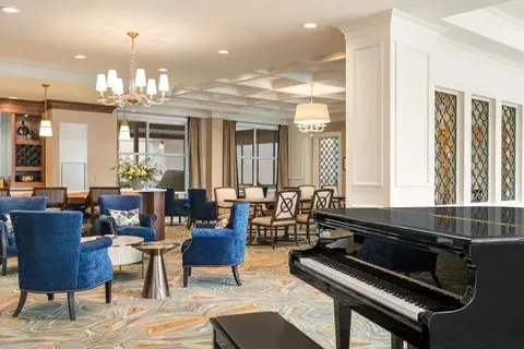 Lounge seating and a grand piano beside large windows.