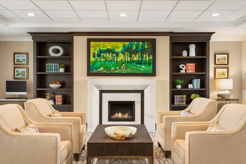 Library lounge with armchairs, bookshelves and a fireplace.