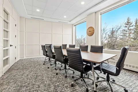 Meeting room with a long table, black chairs and windows