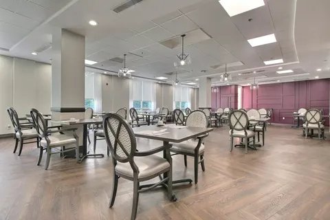 Dining room with set tables, upholstered chairs and pink wall panels