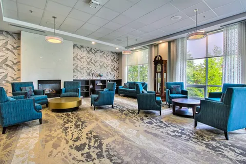 Room with blue armchairs, a fireplace and patterned wallpaper