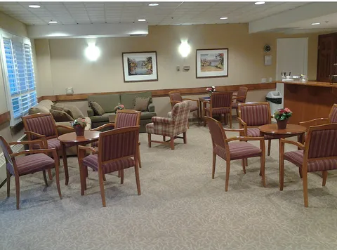 Room with a sofa, striped armchairs, round tables and a kitchenette