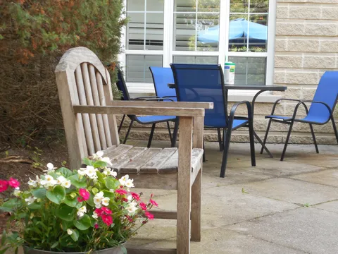 Patio with wooden and blue chairs beside flowering plants