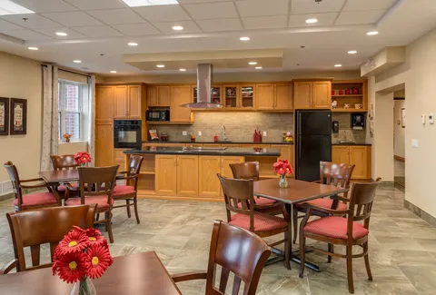 Tables and wooden chairs beside a kitchen with wood cupboards