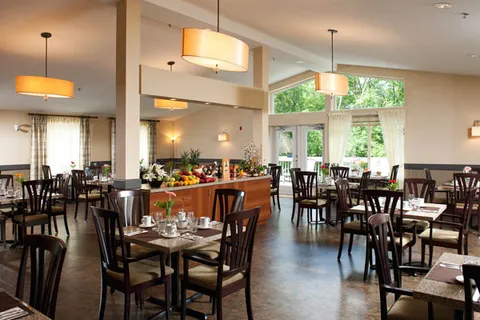 Dining room with wooden tables, chairs and tall windows