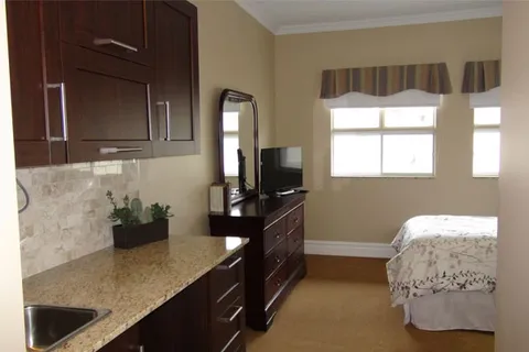 Bedroom with wooden cabinets and a kitchenette beside the bed