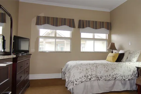 Bedroom with a bed and television beneath two windows