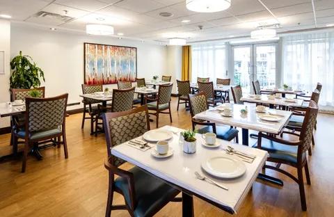 Dining tables with place settings beside windows and an abstract painting