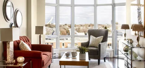 Sofa and armchair beside a coffee table and large corner windows
