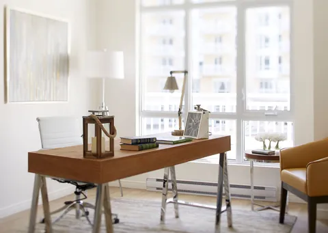 Desk with a white chair, lamp and lantern beside a window