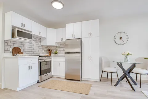 Kitchen with white cabinets, a stove, refrigerator and dining table.