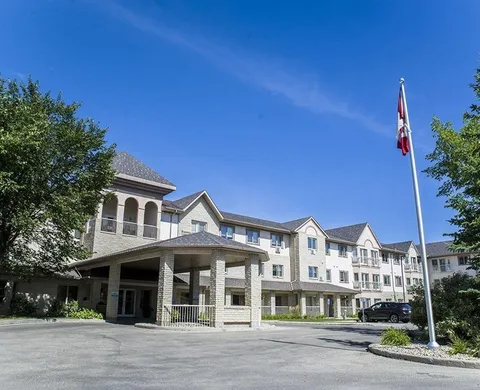 Residence building and covered entrance beside a driveway and flagpole.