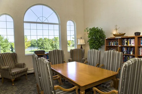 Library lounge with bookcases, armchairs and arched windows.