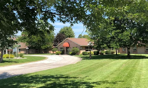 Single-storey residence beside a curved driveway, lawns and trees.