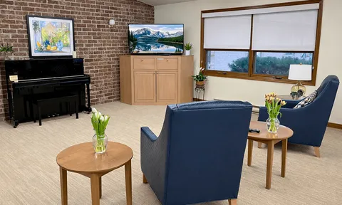 Lounge with blue armchairs, a piano and a television.